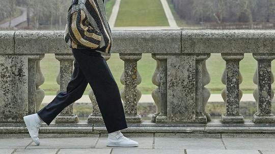 person walking clothing footwear shoe pants sneaker accessories bag handbag